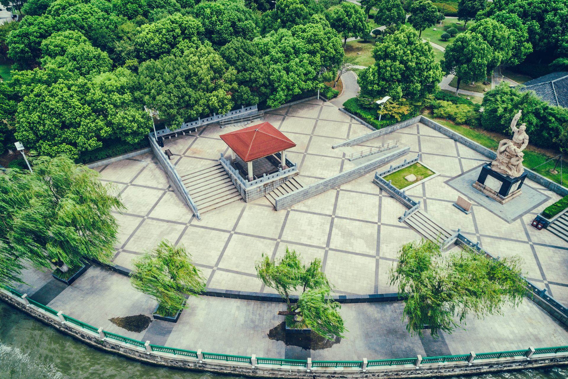 Aerial view of a plaza with a gazebo, statue, and trees, likely a park or public space.
