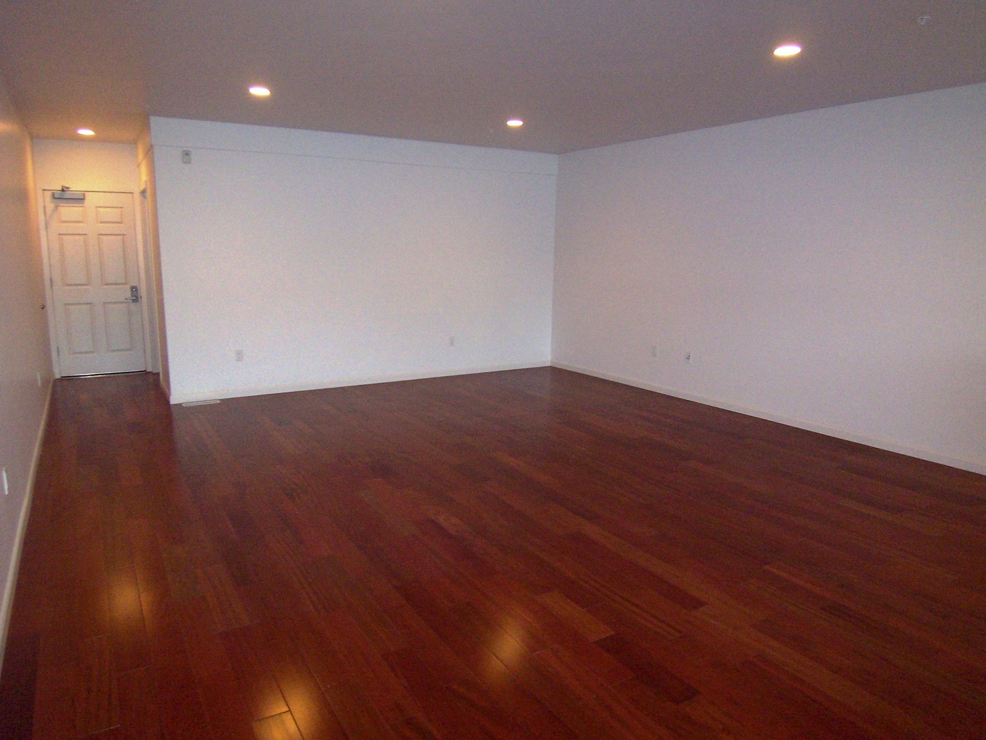 An empty room with hardwood floors and white walls