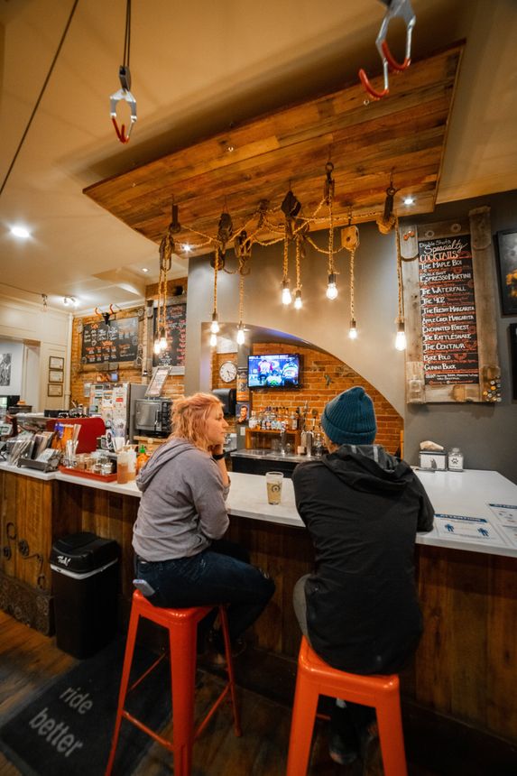 A man and a woman are sitting at a bar in a restaurant.