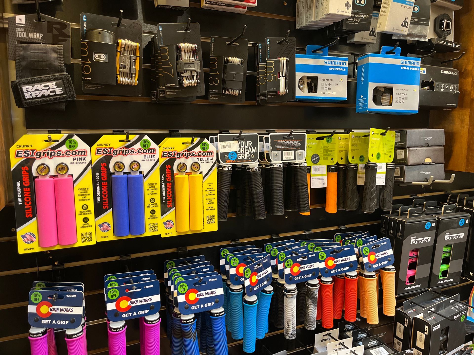 A variety of bicycle grips are displayed on a shelf in a store.