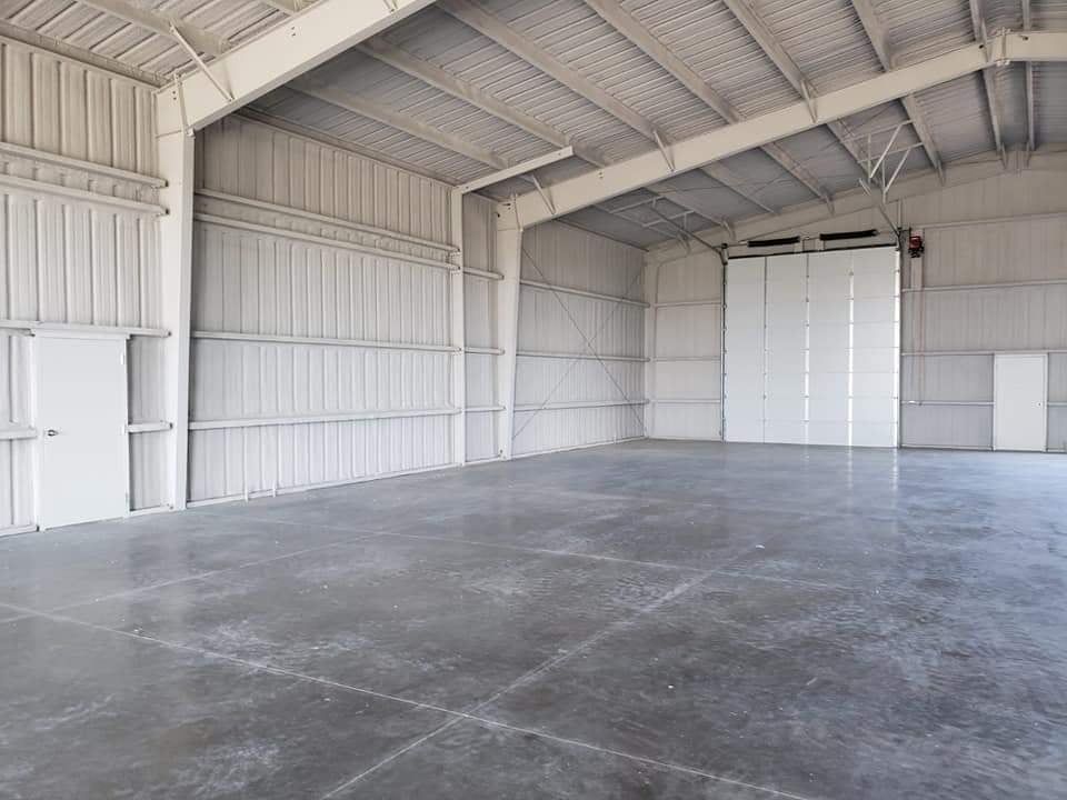 Empty, gray warehouse interior with large concrete floor, metal walls, and overhead door.
