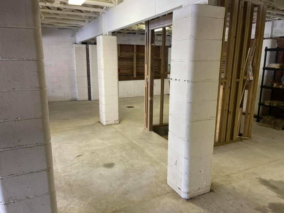 Basement with white cinder block support columns and exposed wooden framing.