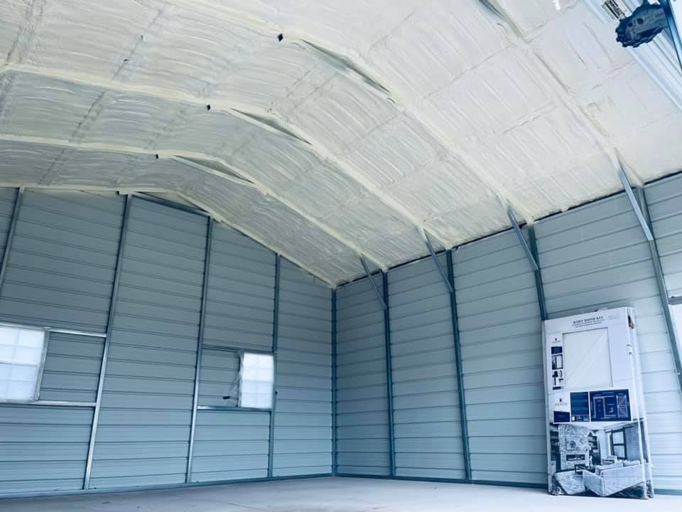 Interior of a metal building with spray foam insulation on the roof, gray walls.