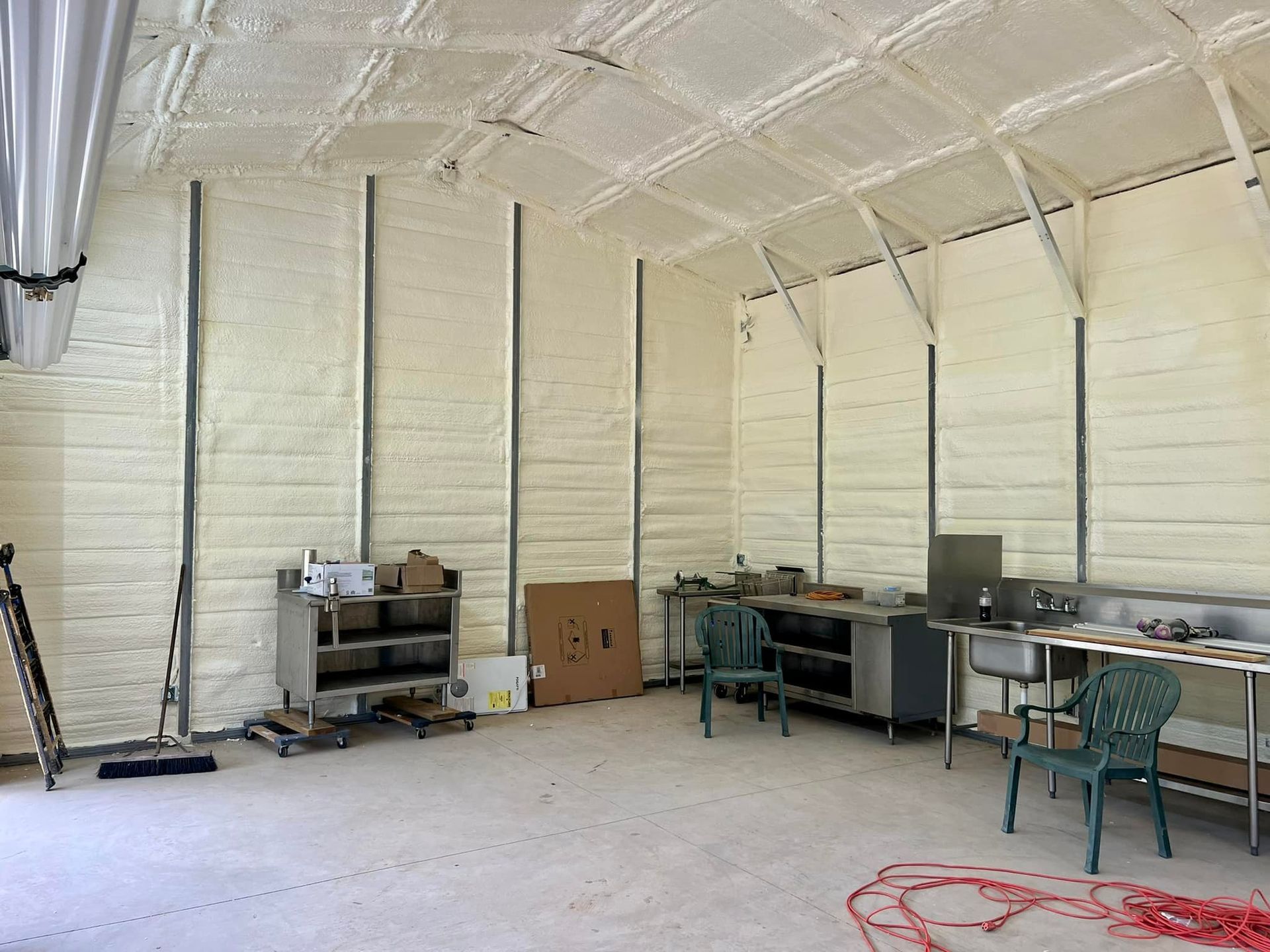 Interior of a room with foam insulation on walls and ceiling, metal framing, and work stations.