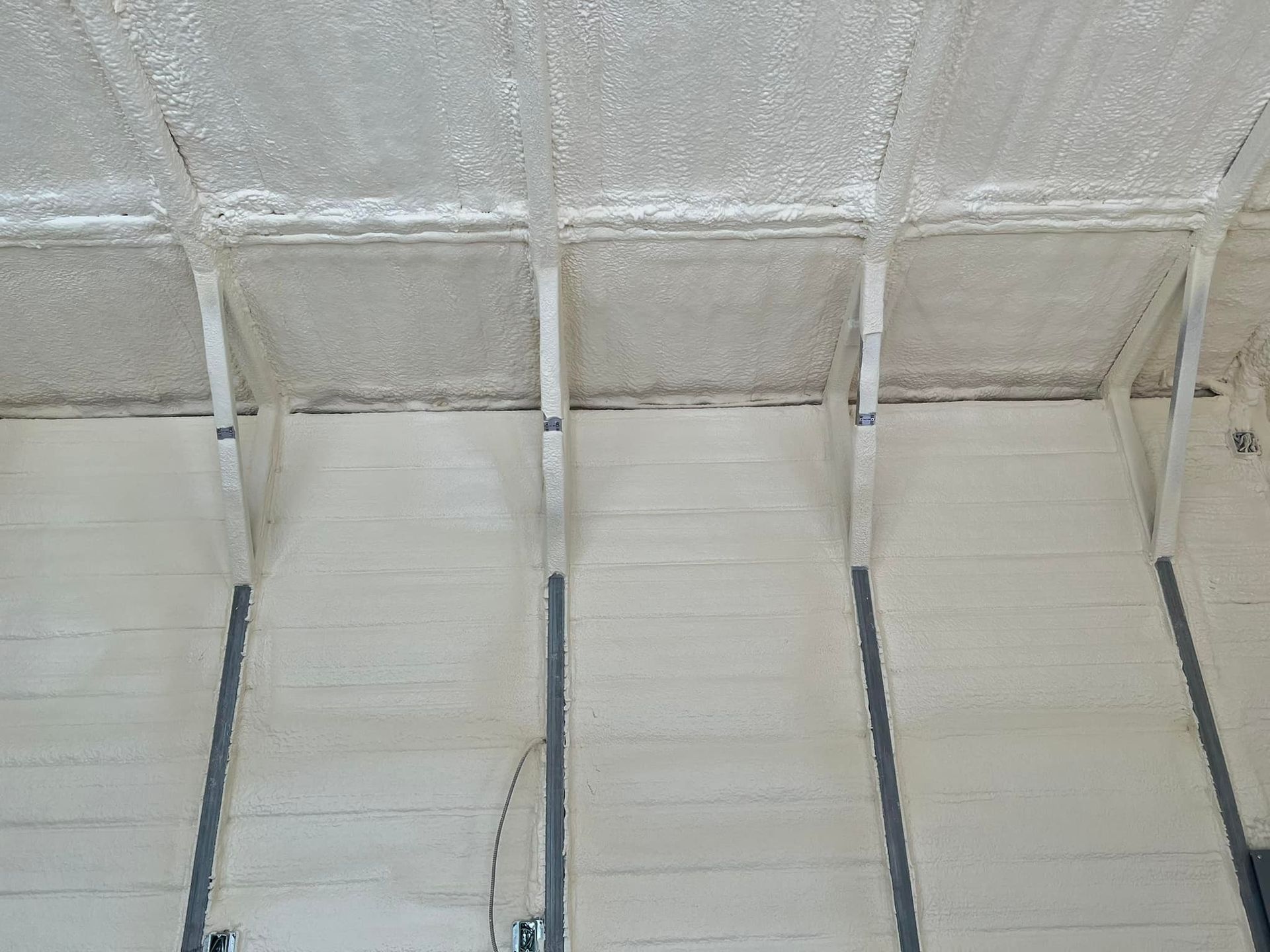Spray foam insulation on ceiling and walls. White with metal supports.