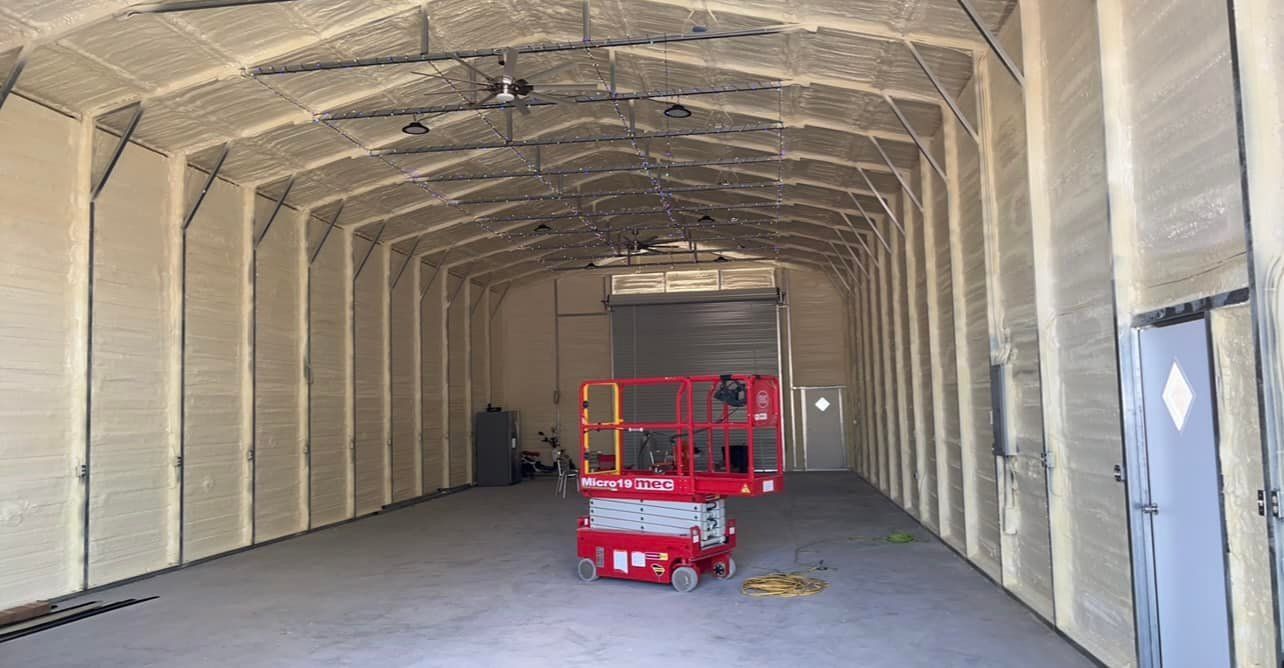 Interior of a metal building with spray foam insulation. A red lift is in the center.