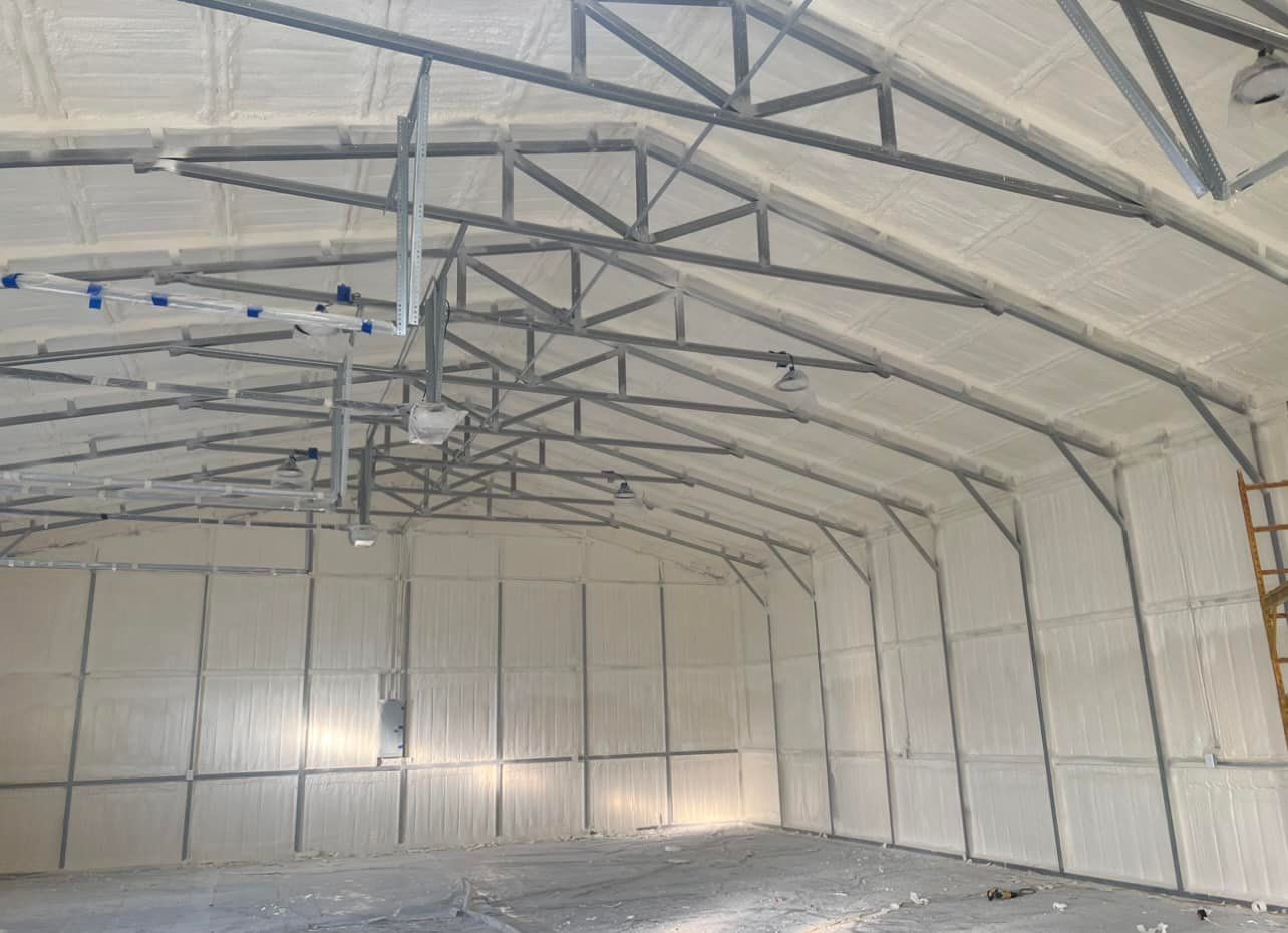 Interior view of a building with white foam insulation on the walls and ceiling, steel beams supporting the structure.