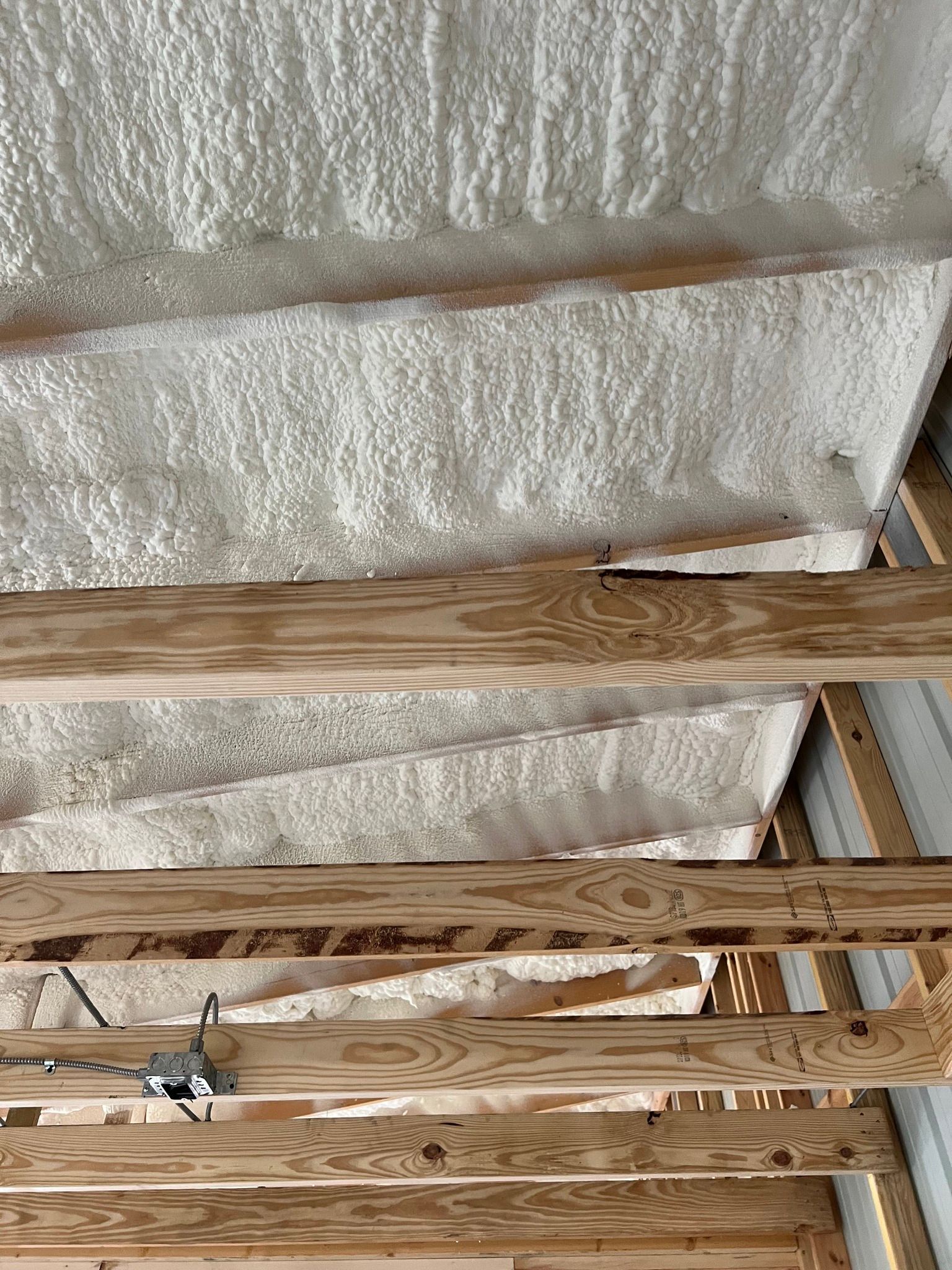 Spray foam insulation on ceiling with wooden beams.