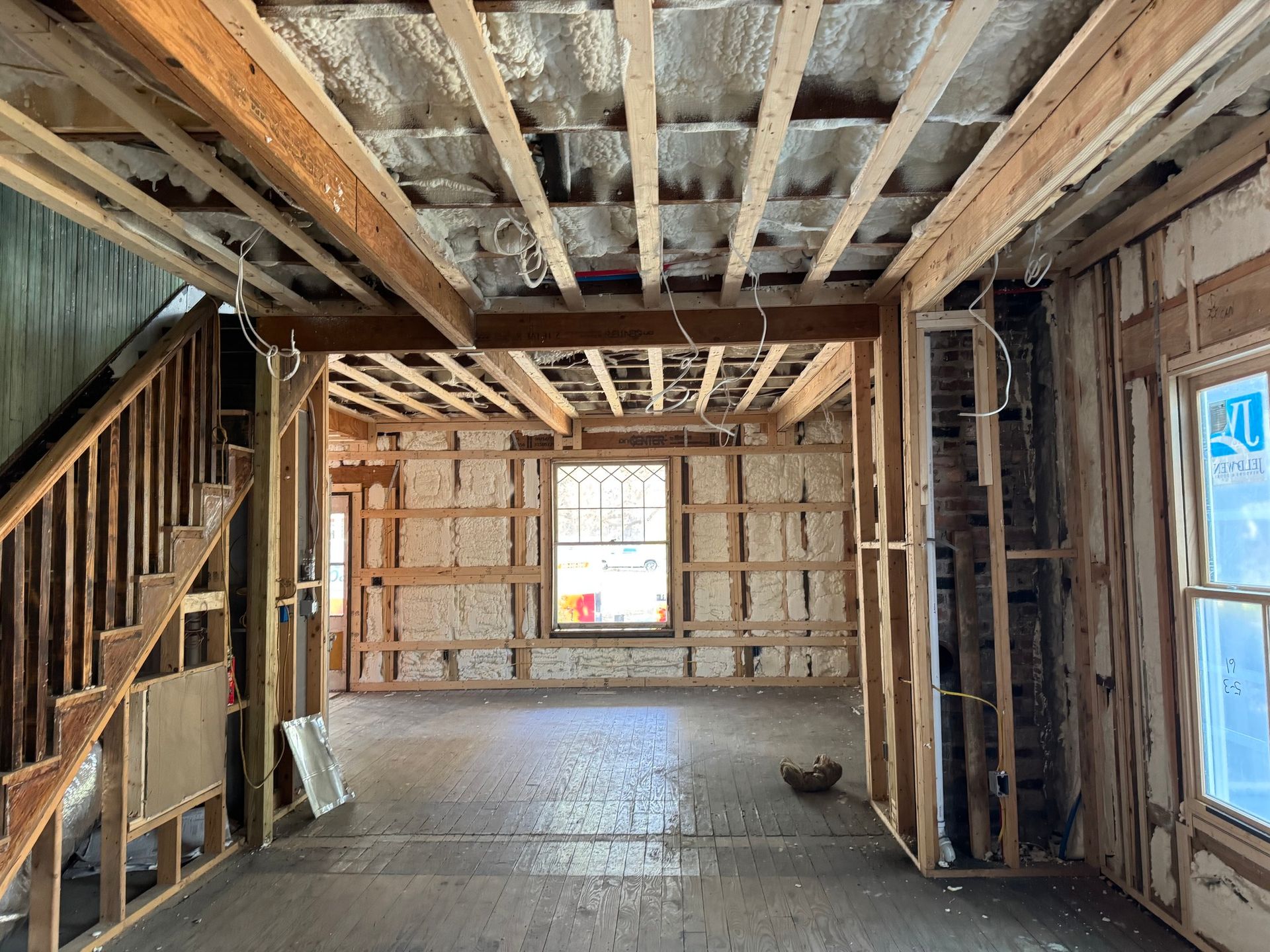 Interior of a house under renovation, exposed framing, insulation, and stairs.