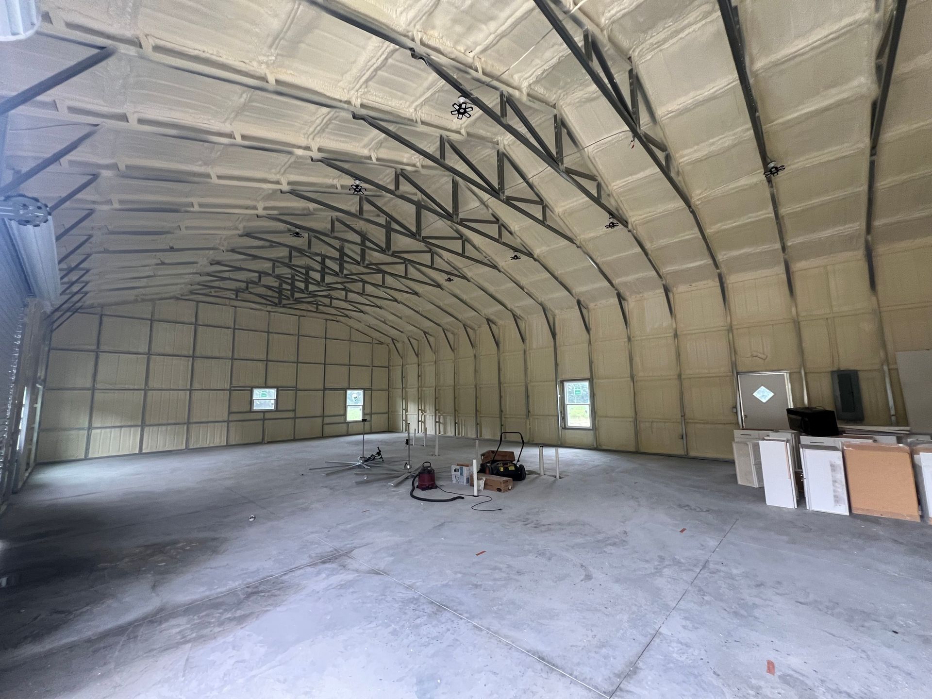 Interior view of a large, insulated arched metal building with concrete floor and open space.
