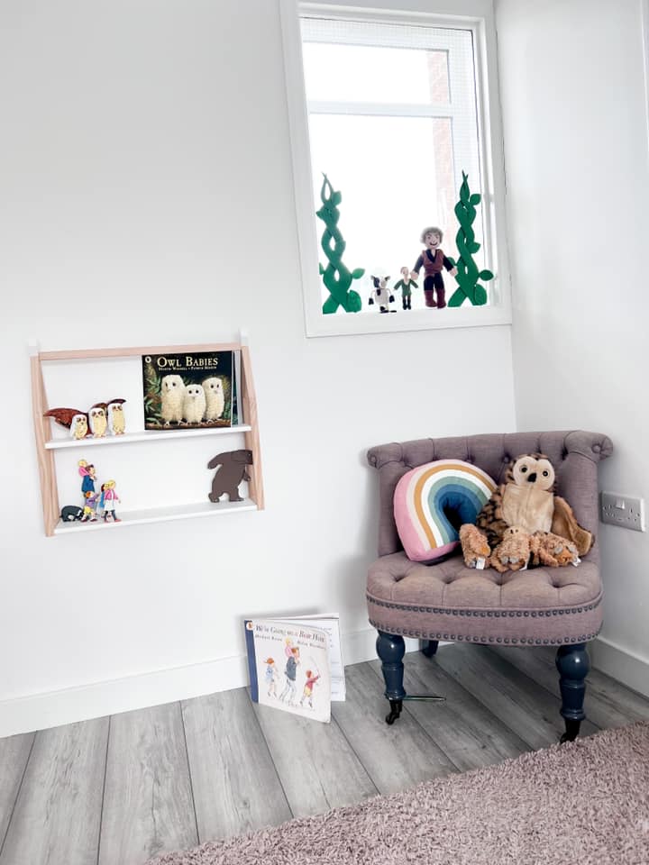 A child 's room with a chair , bookshelf , and window.