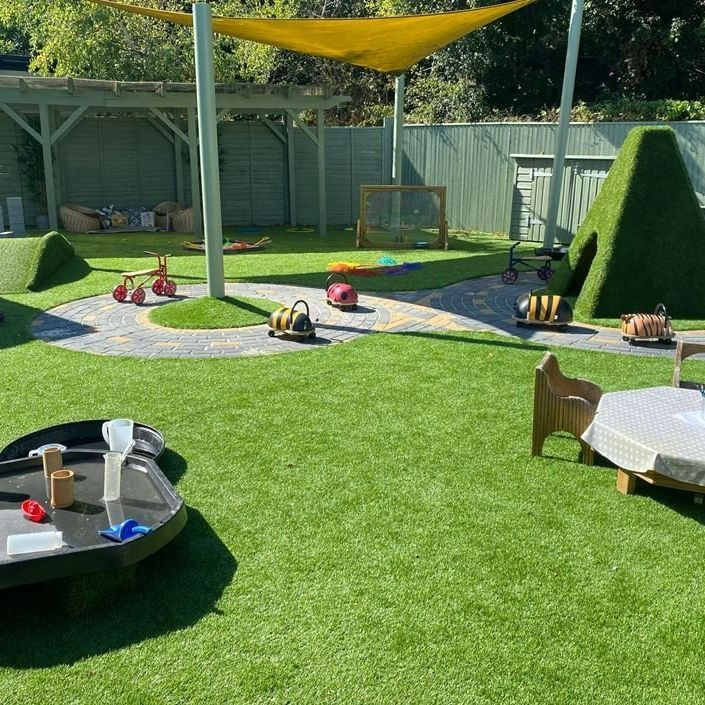 A playground with a table , chairs , and toys on the grass.