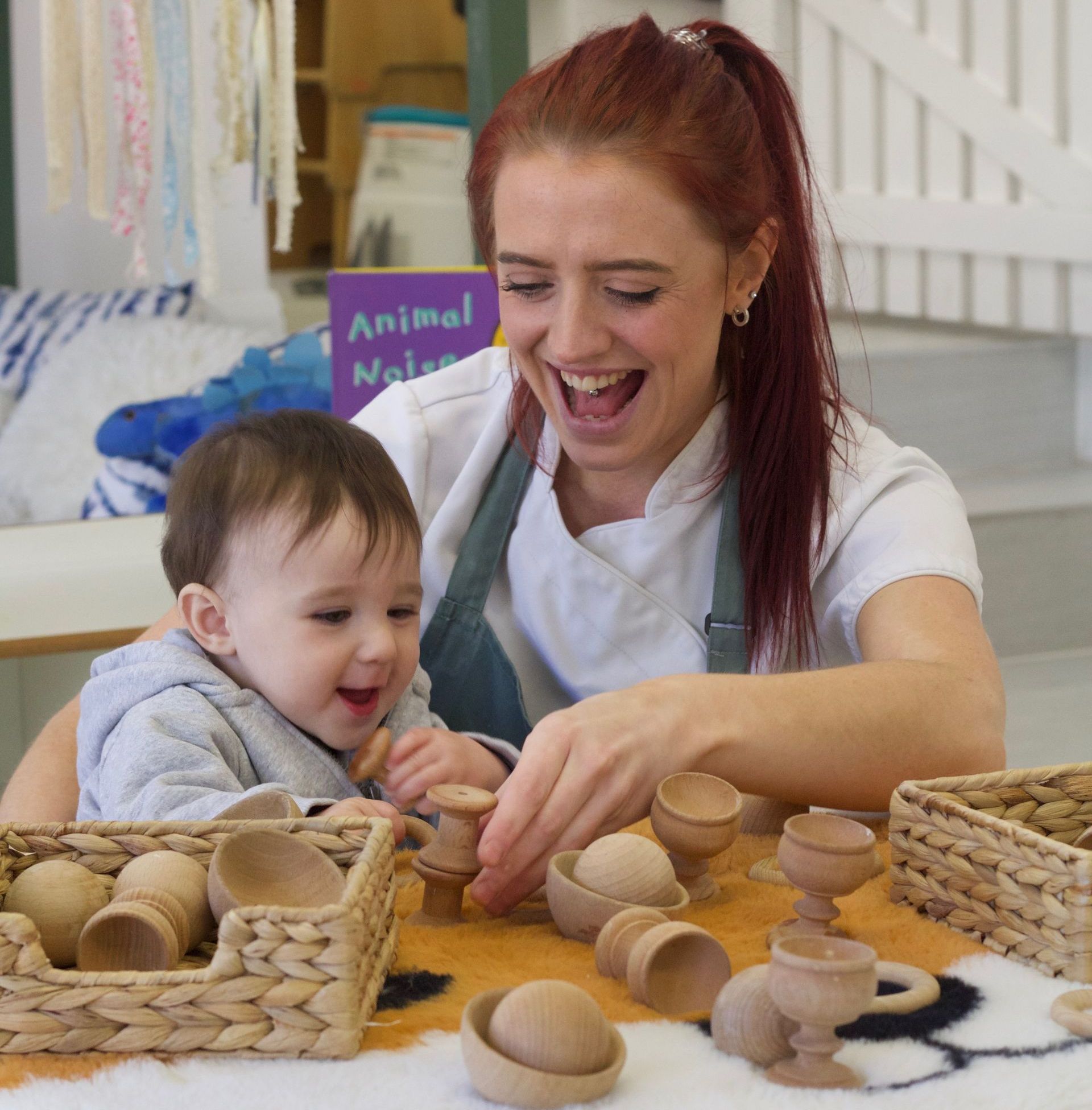 Baby and Nursery Nurse playing with wooden learning resources