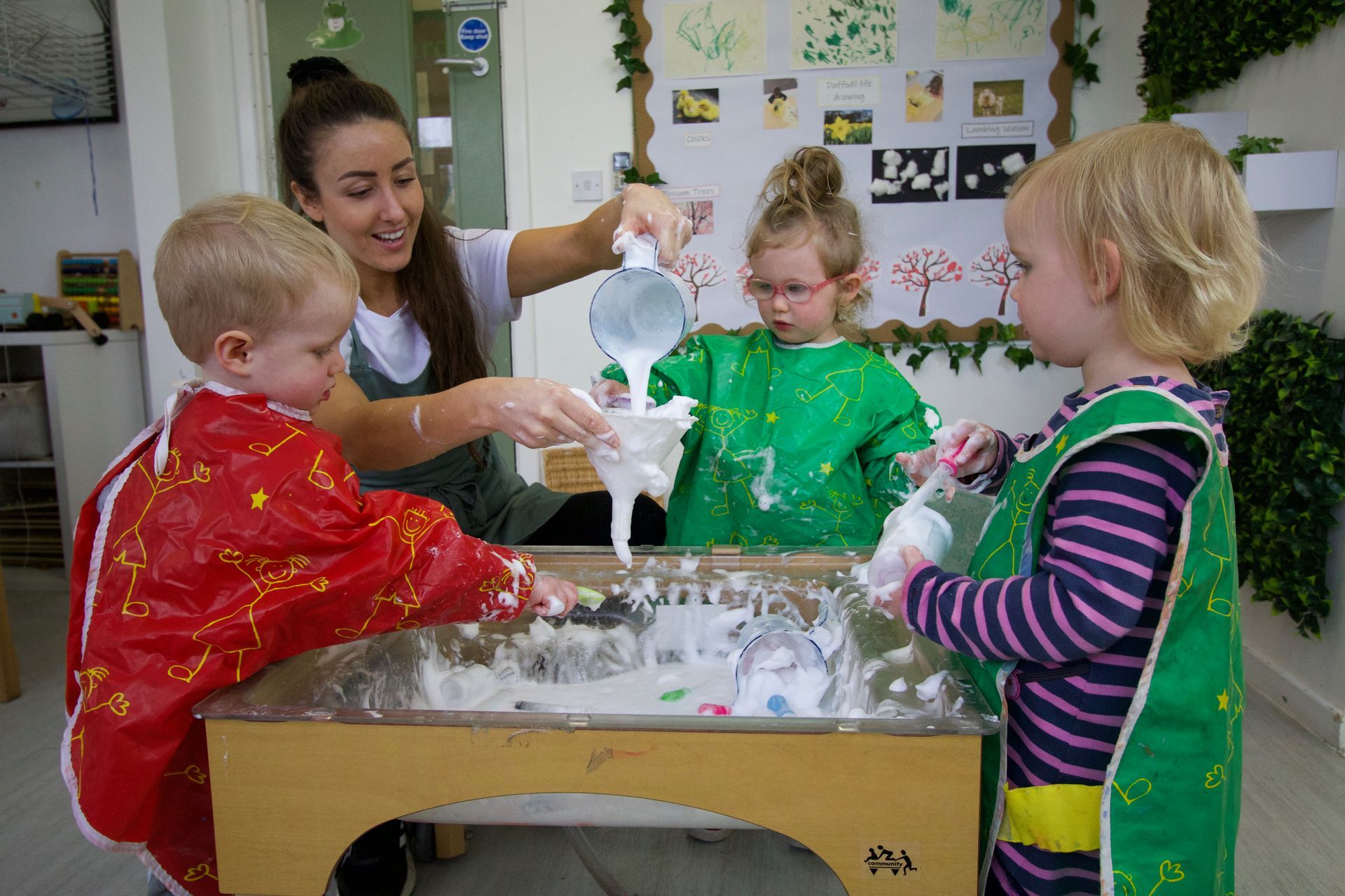 Children enjoying messy play sensory activity with Nursery Nurse