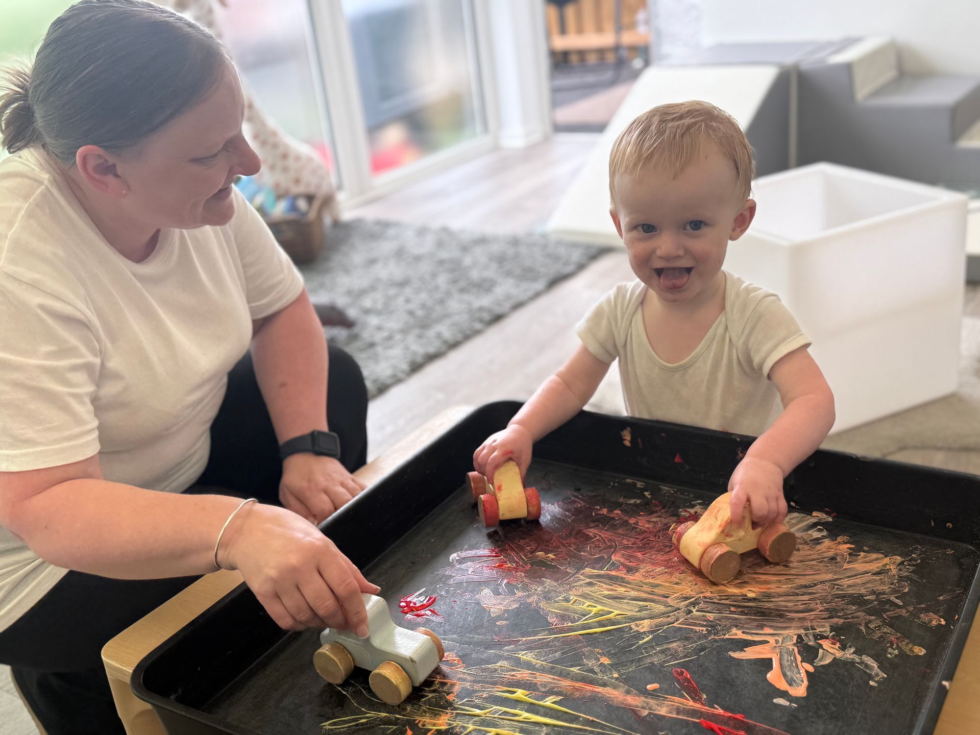 Young child and Nursery Nurse enjoying a messy play activity 