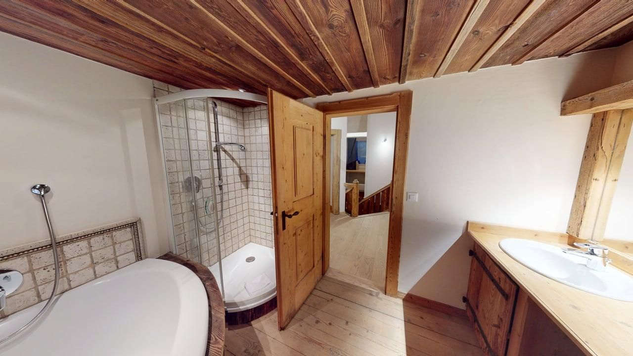 Rustic bathroom with a white oval tub, a glass corner shower, a wooden vanity with a sink, and a wooden paneled ceiling.