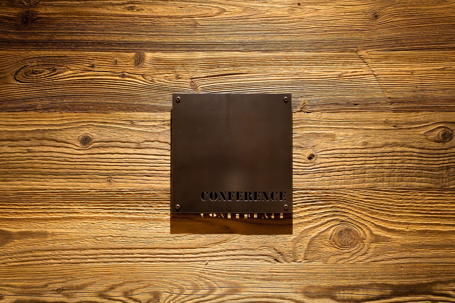 Dark square plaque on a wood-grain surface, with small text along the bottom edge.