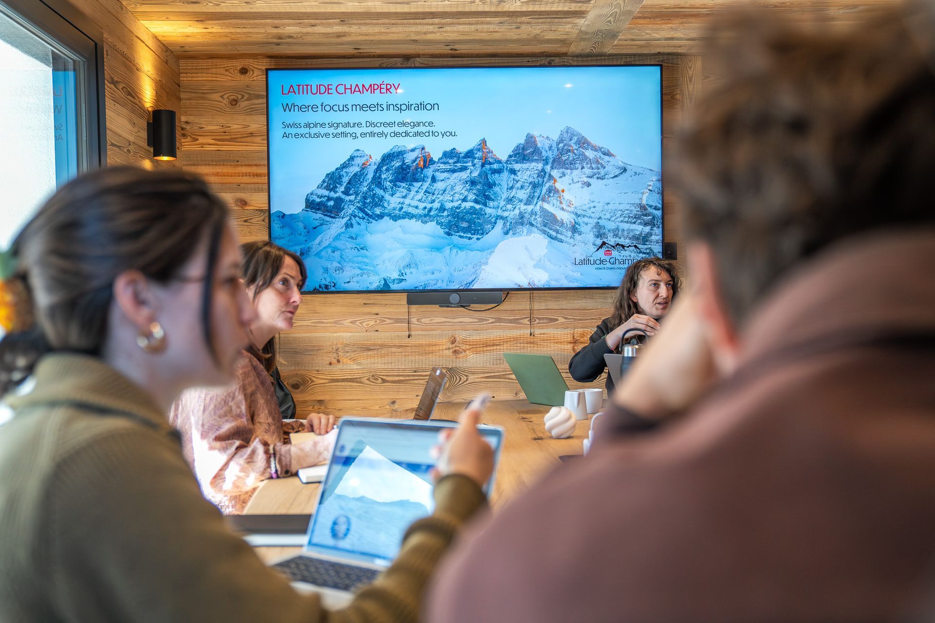 People in a meeting room watching a mountain presentation on a large screen