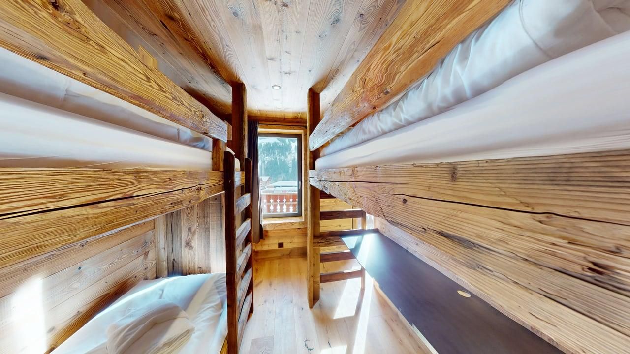 Une cabine rustique et étroite avec des lits superposés en bois de chaque côté et une fenêtre au fond.