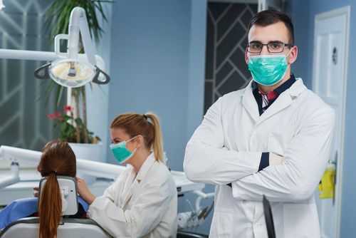Dentist Wearing A Mask Standing In Front Of A Patient In A Dental Chair — Dentist On Tweed in Tweed Heads, NSW