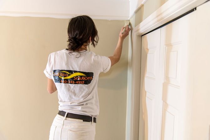 Person painting a wall near white closet doors in a room