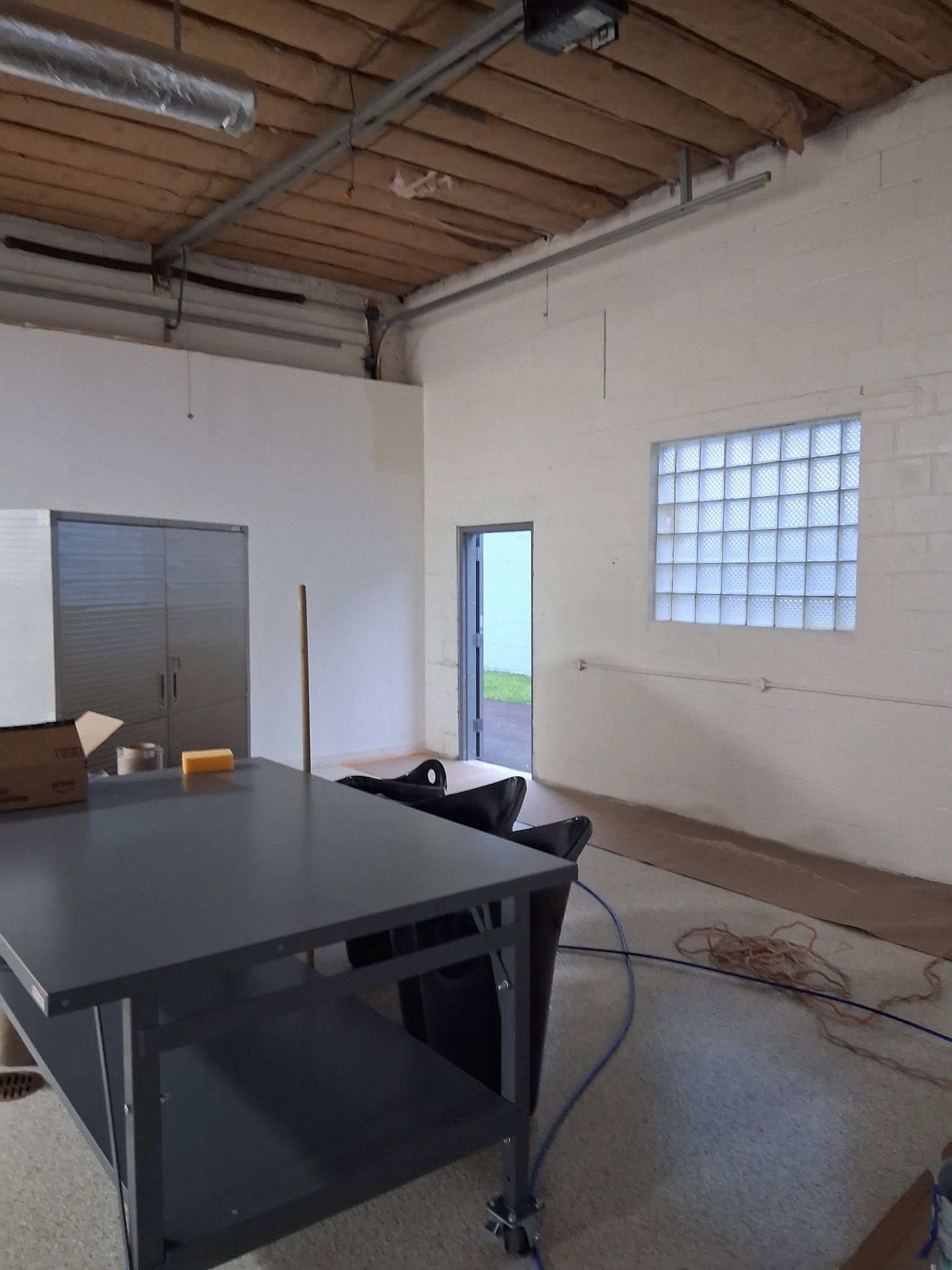 Empty modern warehouse interior with high black ceiling, large windows, and polished concrete floor
