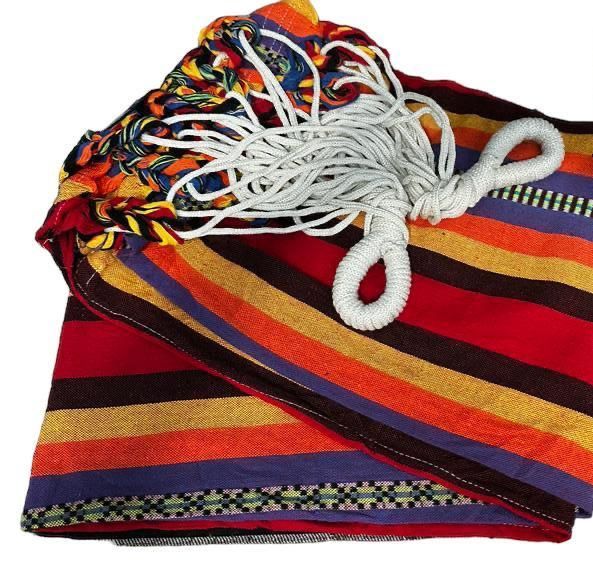 Una hamaca plegada con rayas brillantes y multicolores de color rojo, naranja, amarillo y morado