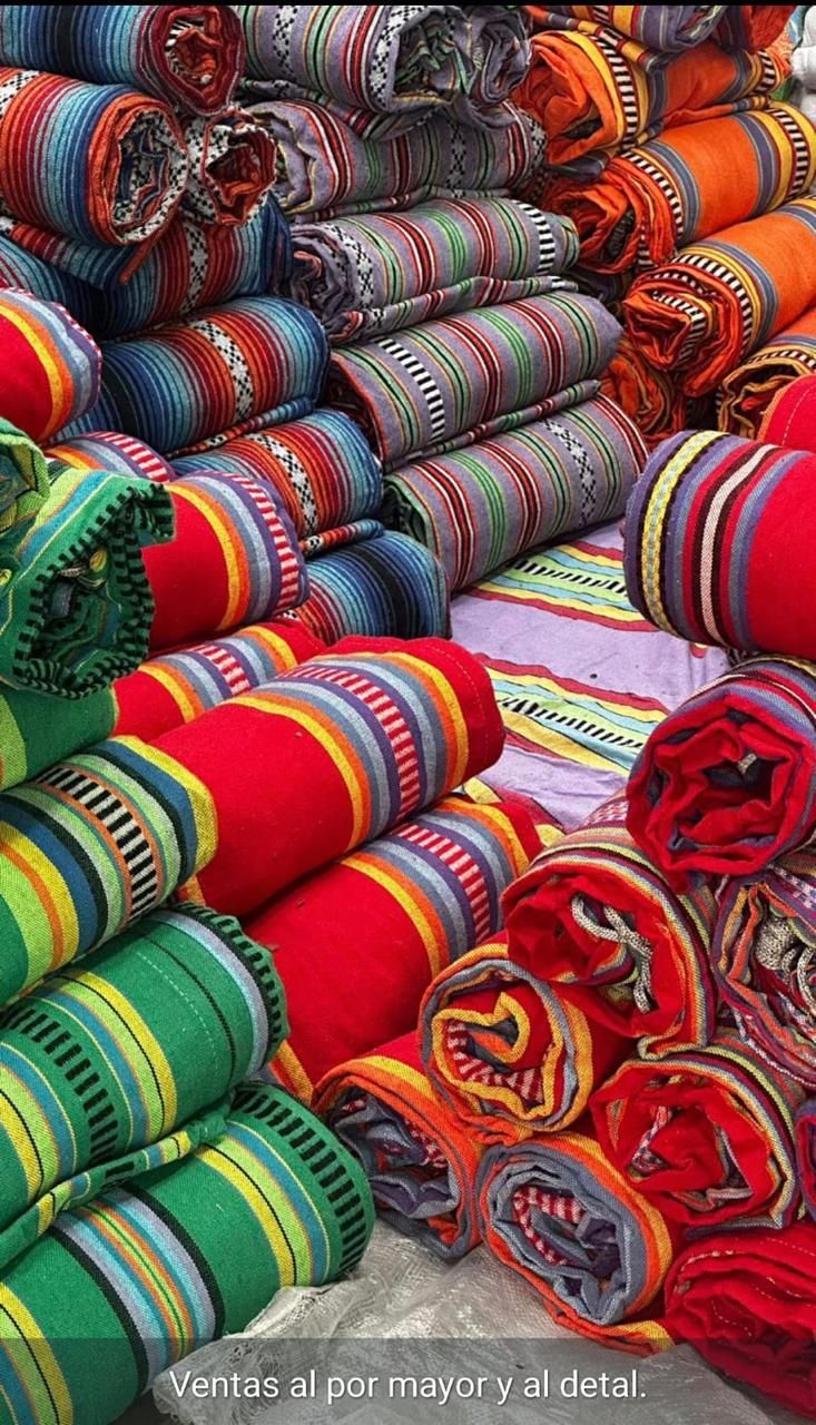 Montones de mantas y textiles coloridos, estampados y tejidos a mano, dispuestos para la venta.