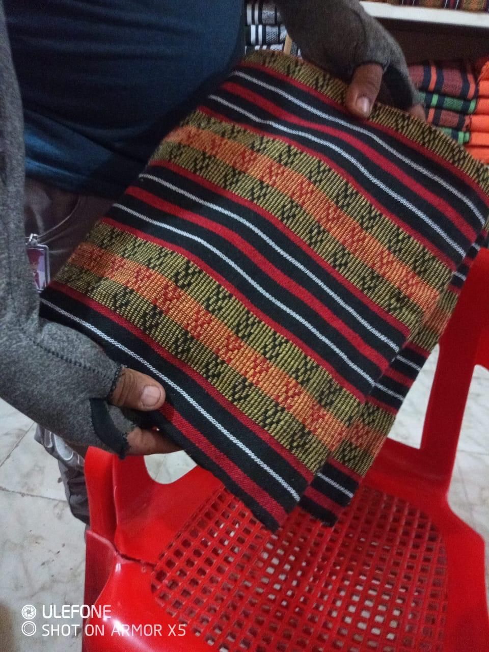 Unas manos sostienen un trozo de tela doblado con motivos geométricos 