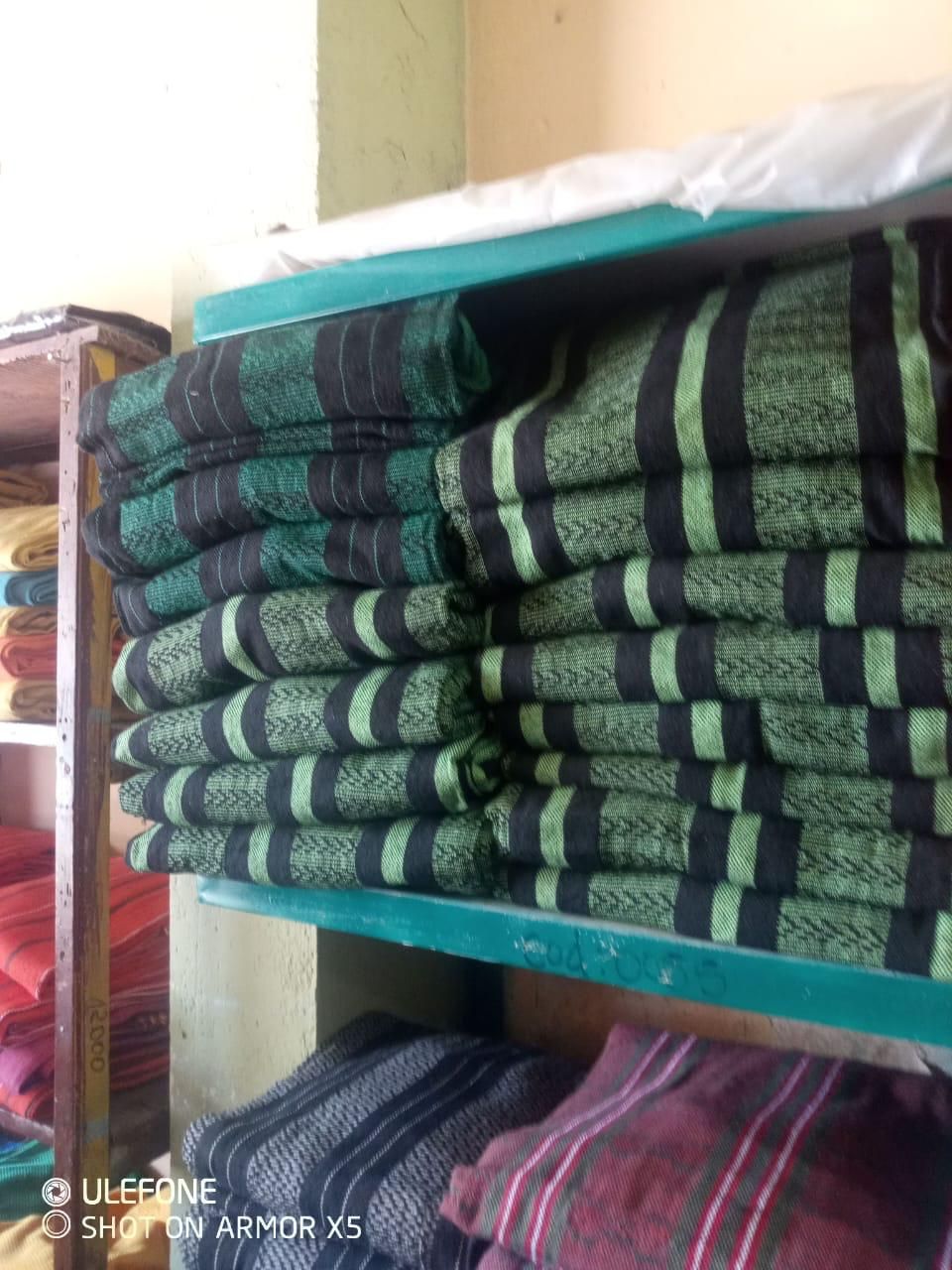 Mantas apiladas, dobladas y con estampados verdes y negros, en un estante de un área de almacenamiento.