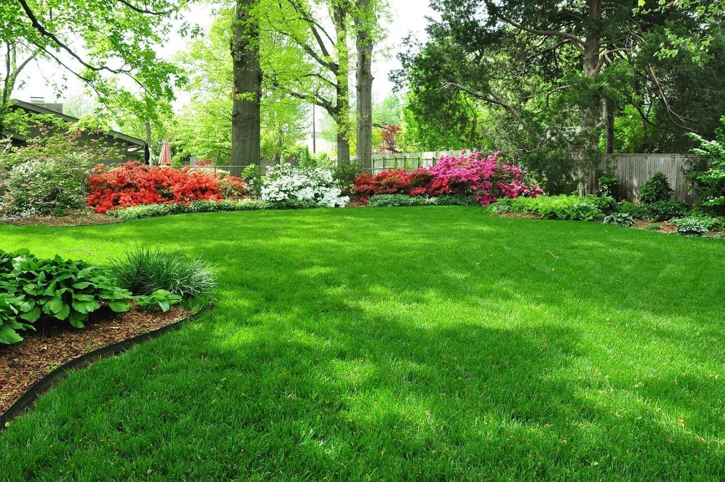 a garden with a stone wall and stairs surrounded by flowers