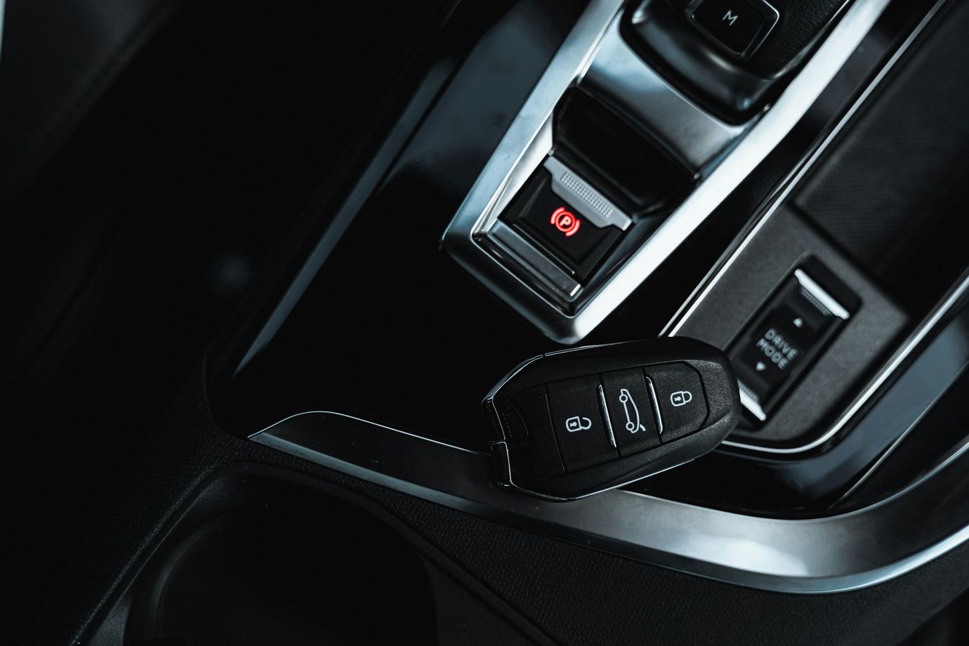 Car key on a black dashboard near electronic buttons.