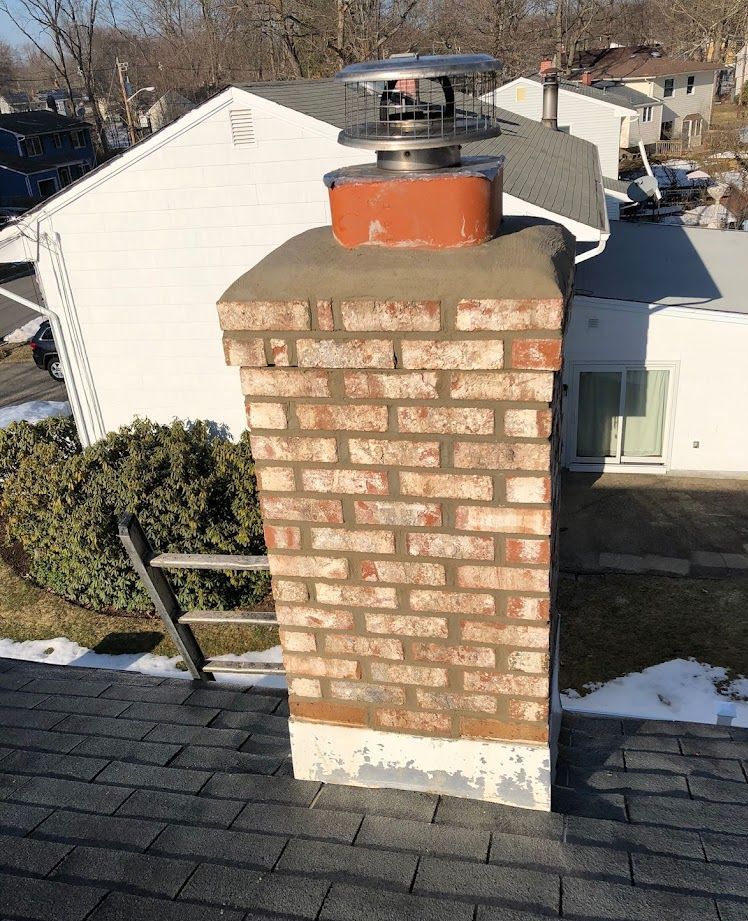 A brick chimney is on the roof of a house.