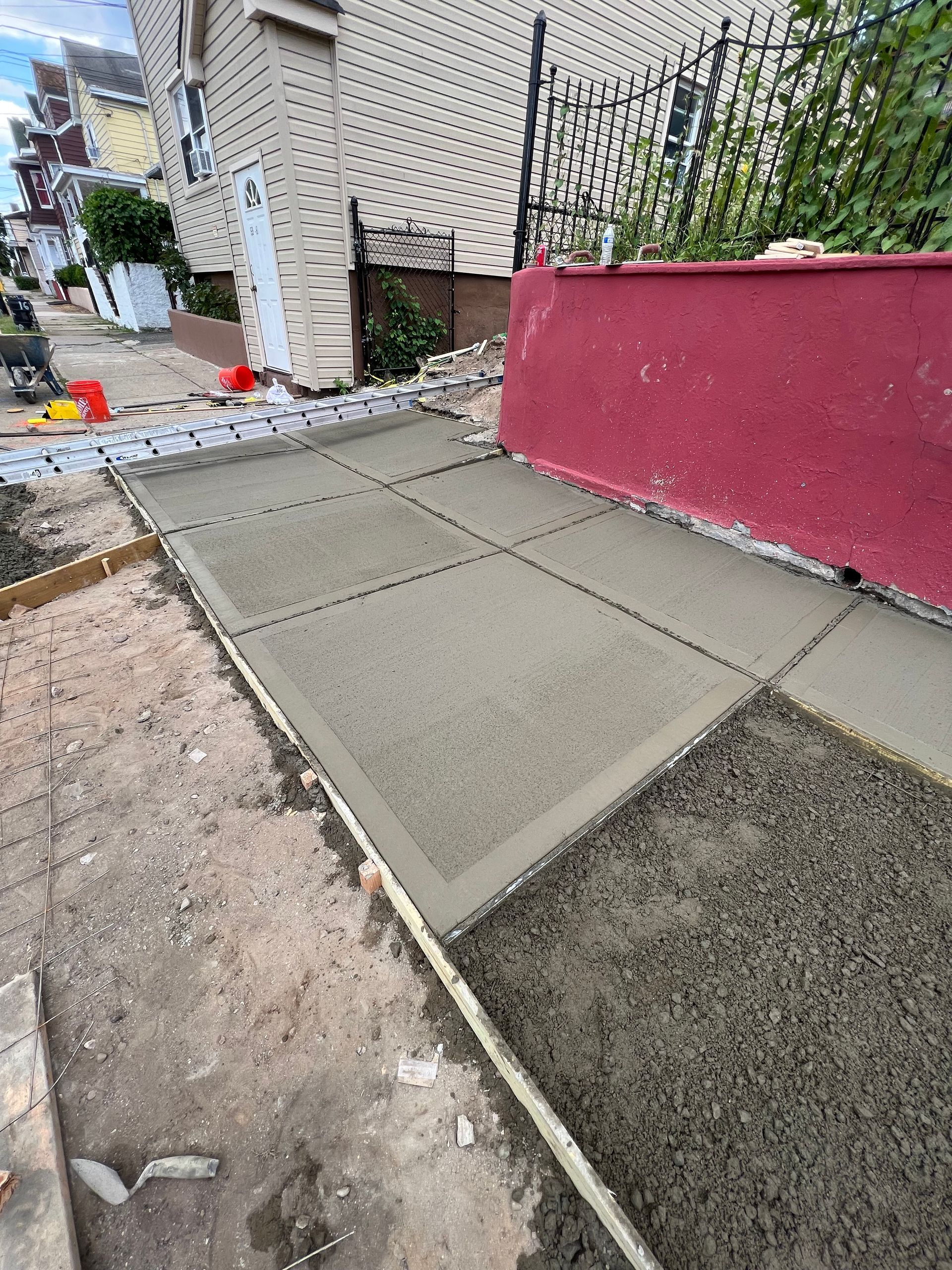 A concrete walkway is being built in front of a house.