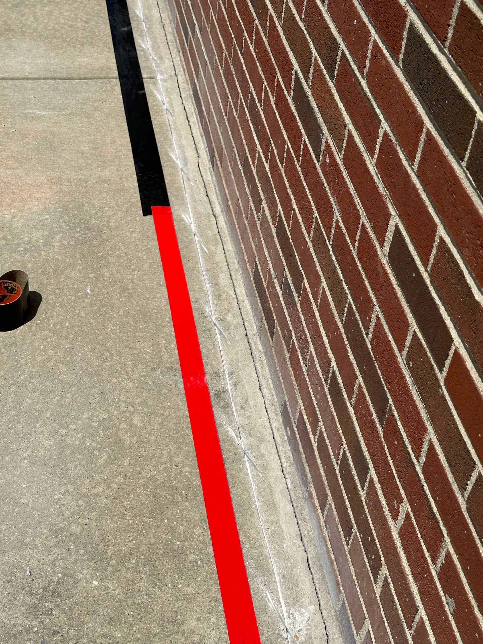 A red line on the sidewalk next to a brick wall