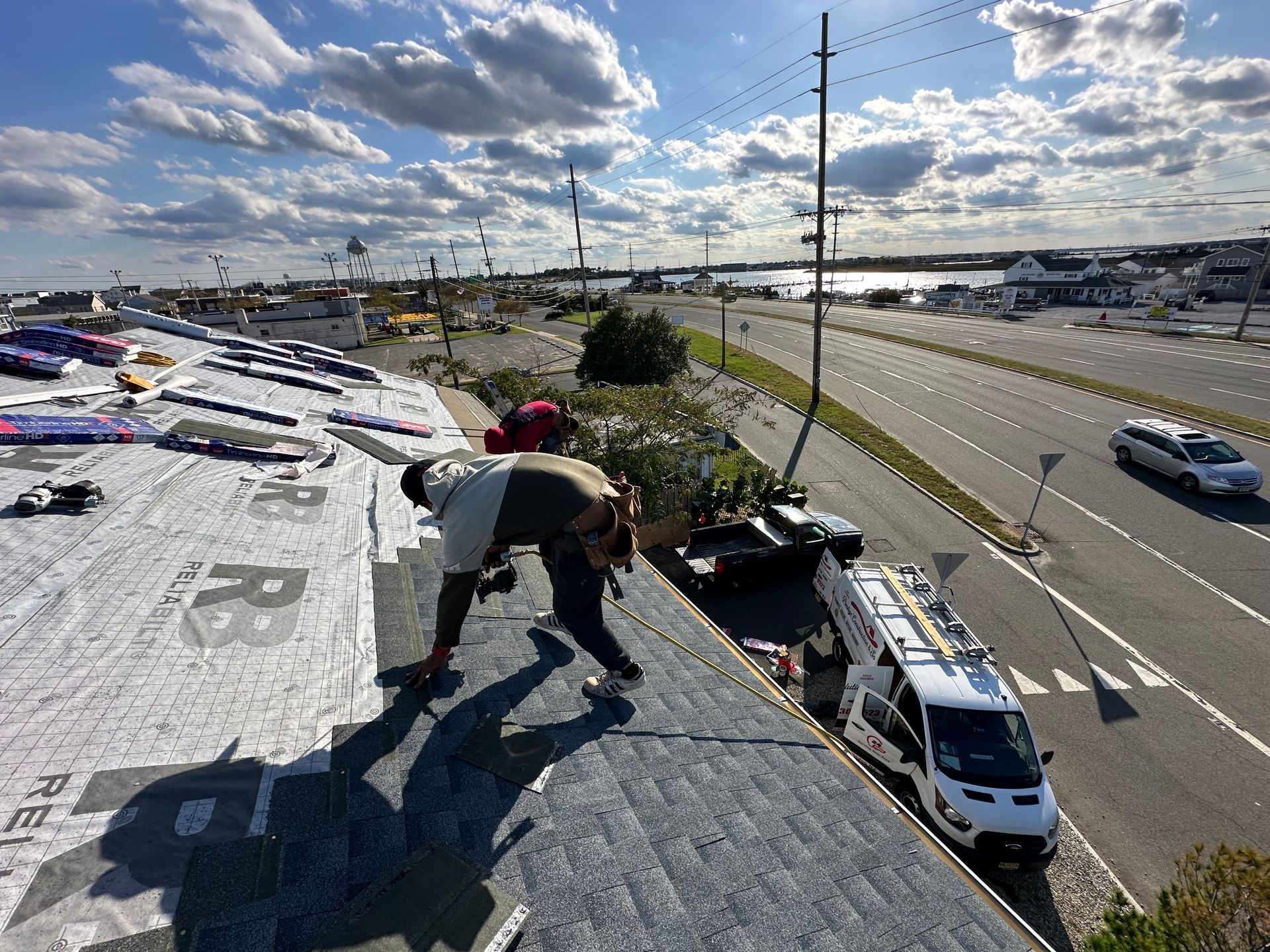 A group of people are working on a roof next to a highway.