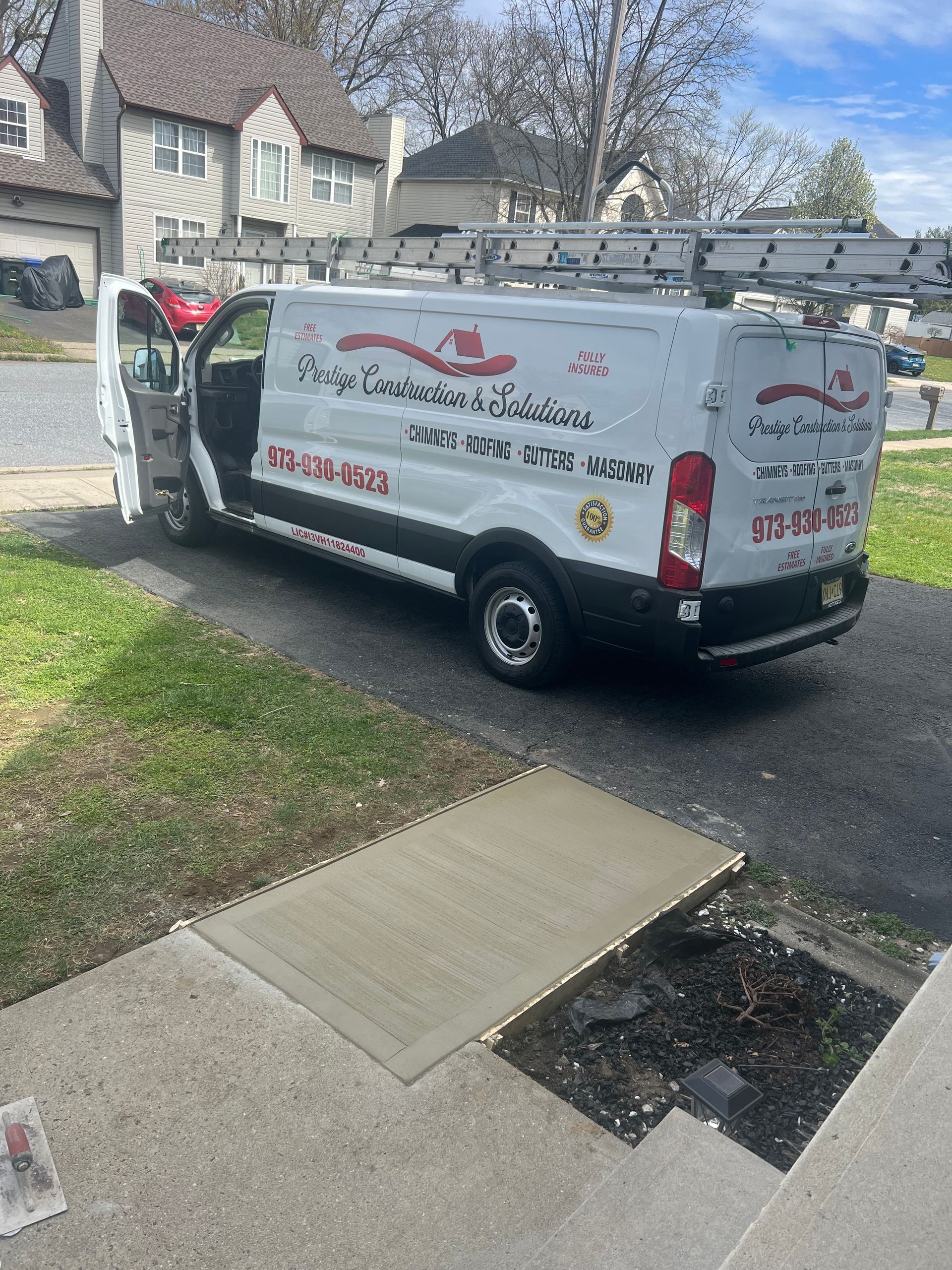A white van is parked in a driveway next to a sidewalk.