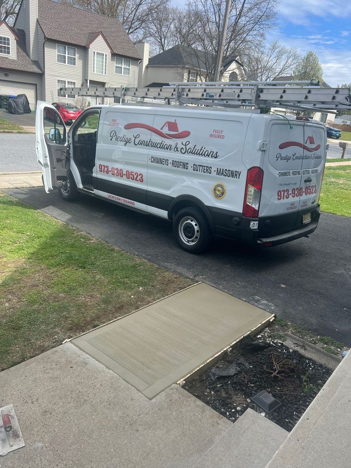 A white van is parked in a driveway next to a sidewalk.