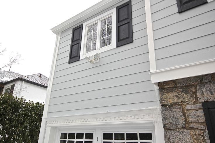 A white house with black shutters and a garage door.