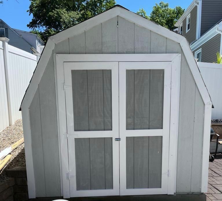 A white barn shaped shed with a screen door