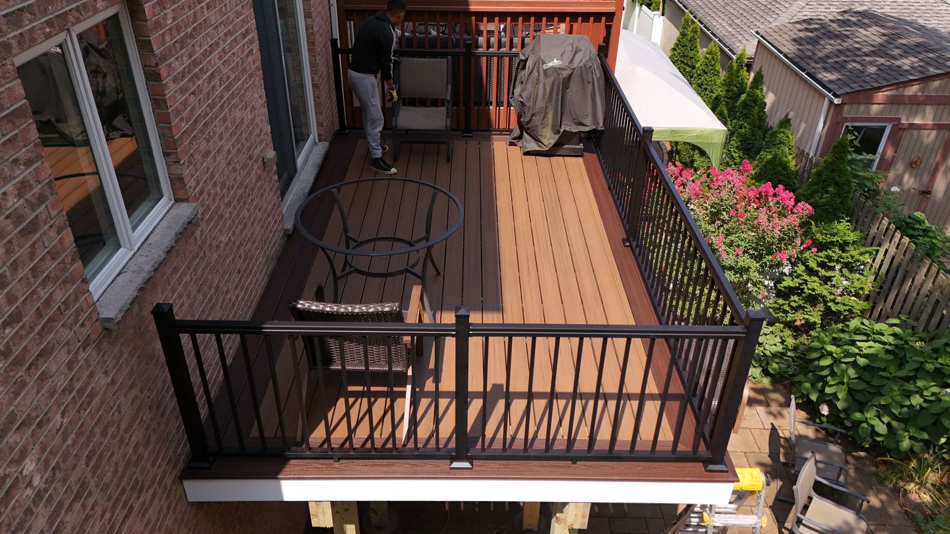An aerial view of a deck with a black railing and a grill.
