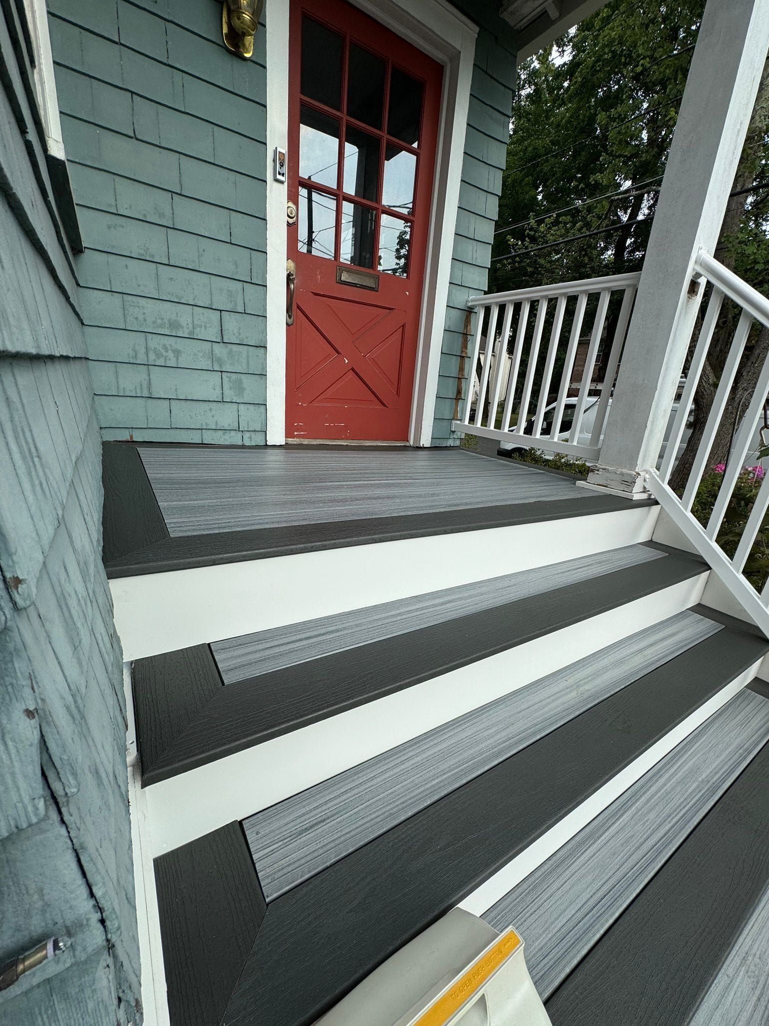 A blue house with a red door and black steps