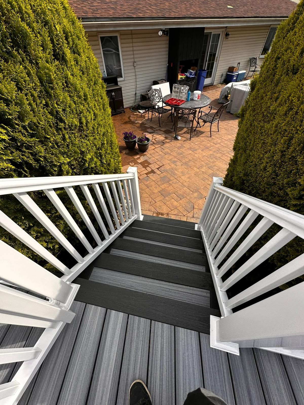 A person is standing on a deck with stairs leading up to a patio.