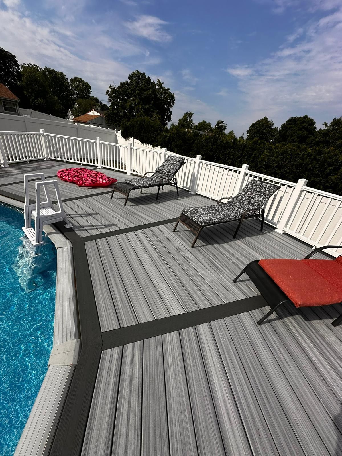 A deck with chairs and a swimming pool in the background