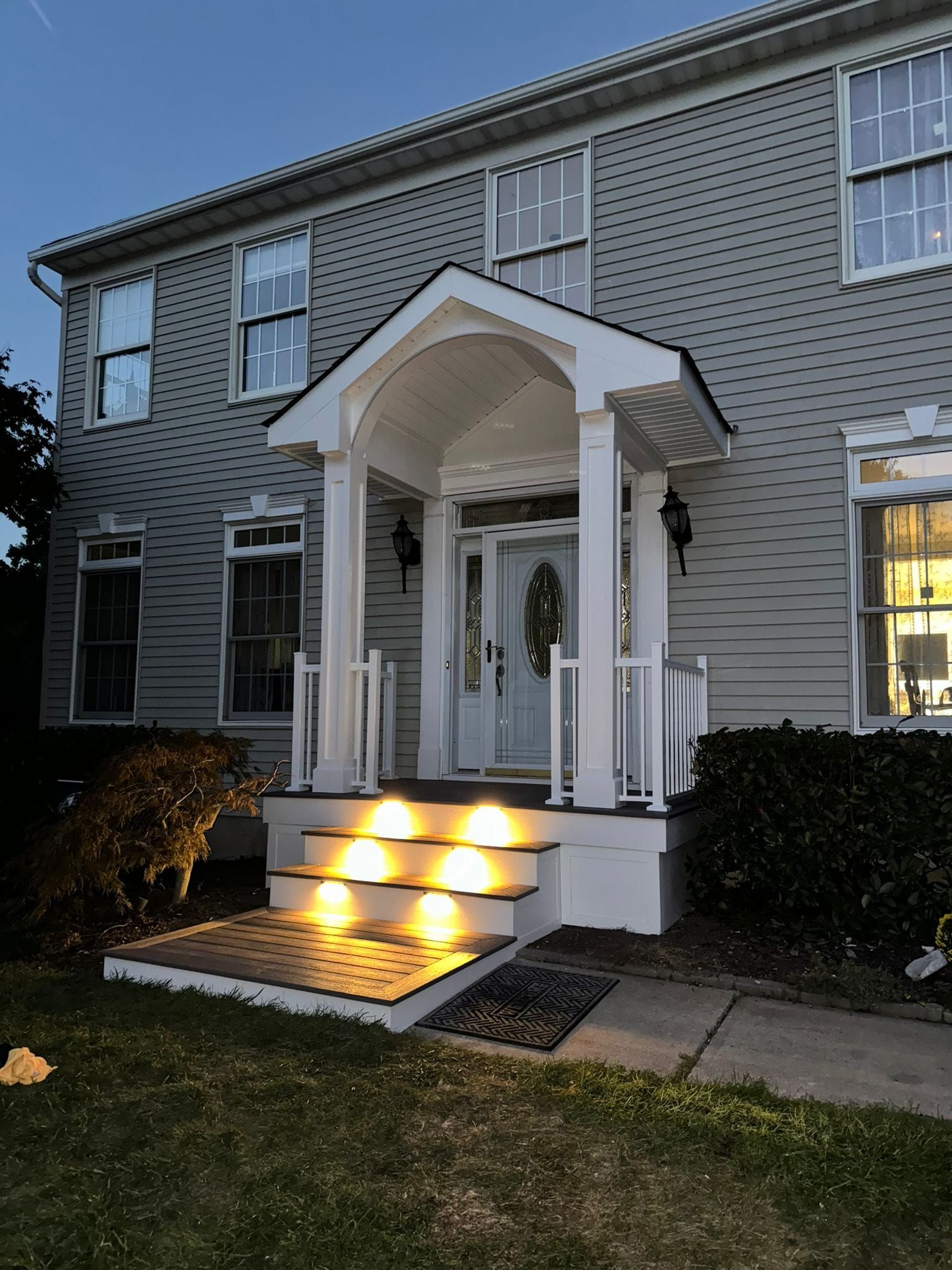 A house with a porch and stairs that are lit up at night