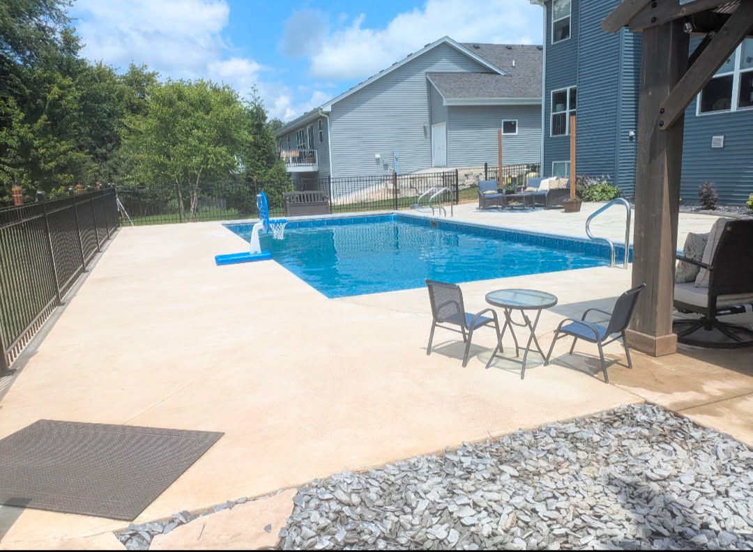 A large oval swimming pool is sitting on a wooden deck