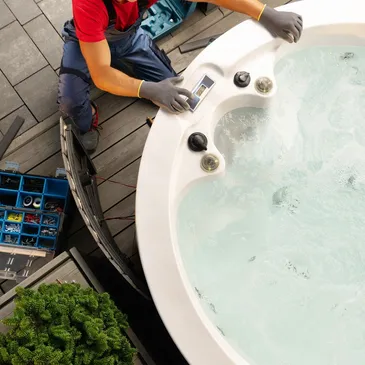 A man is working on a hot tub on a deck.