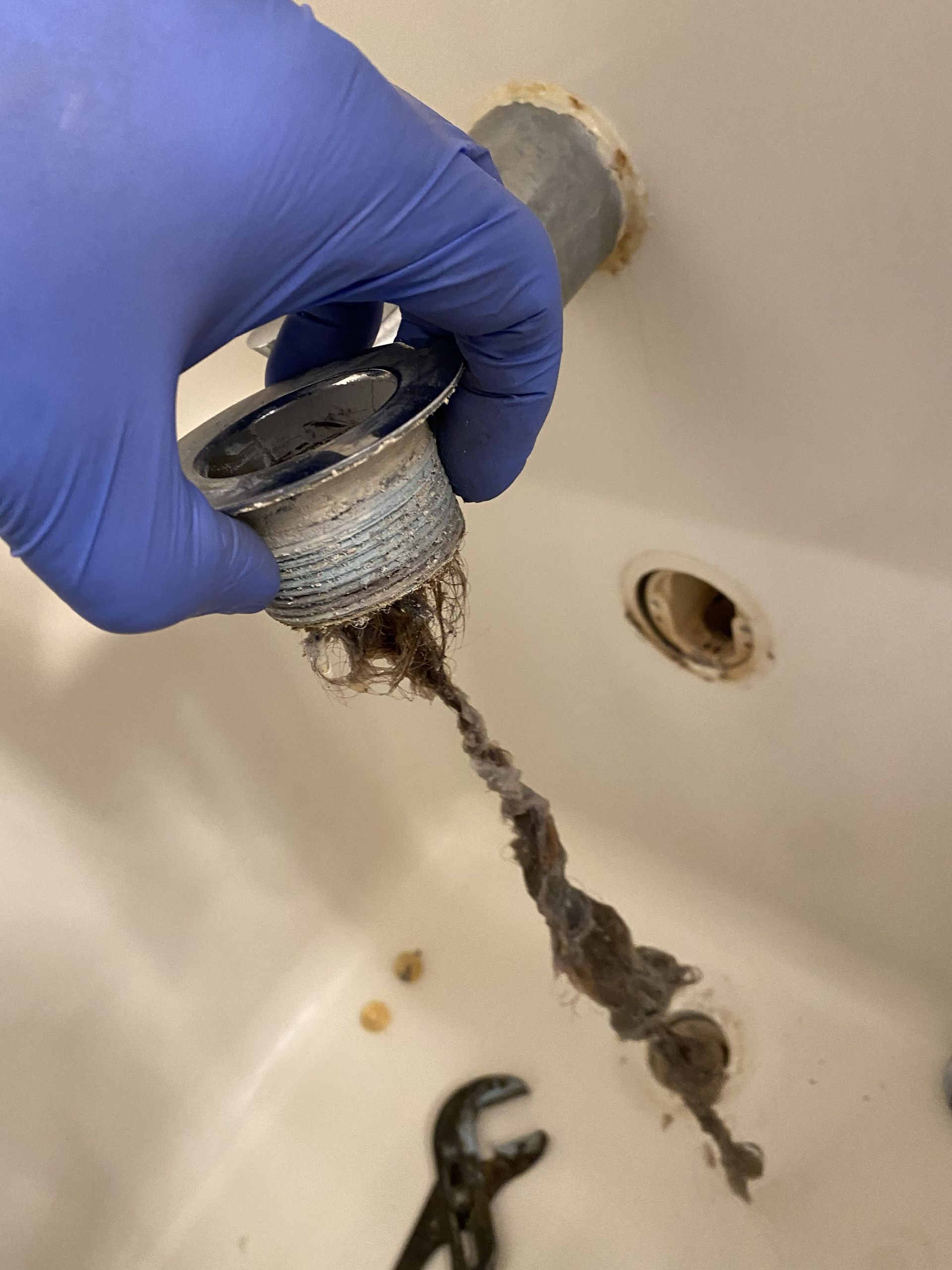 Technician cleaning under a kitchen sink with a vacuum hose and equipment in a utility room