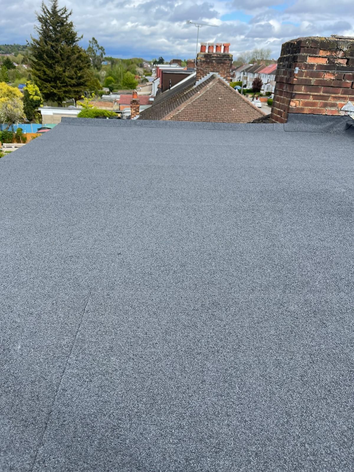 Newly installed flat roof with dark grey mineral felt by a roofer in Wimbledon.