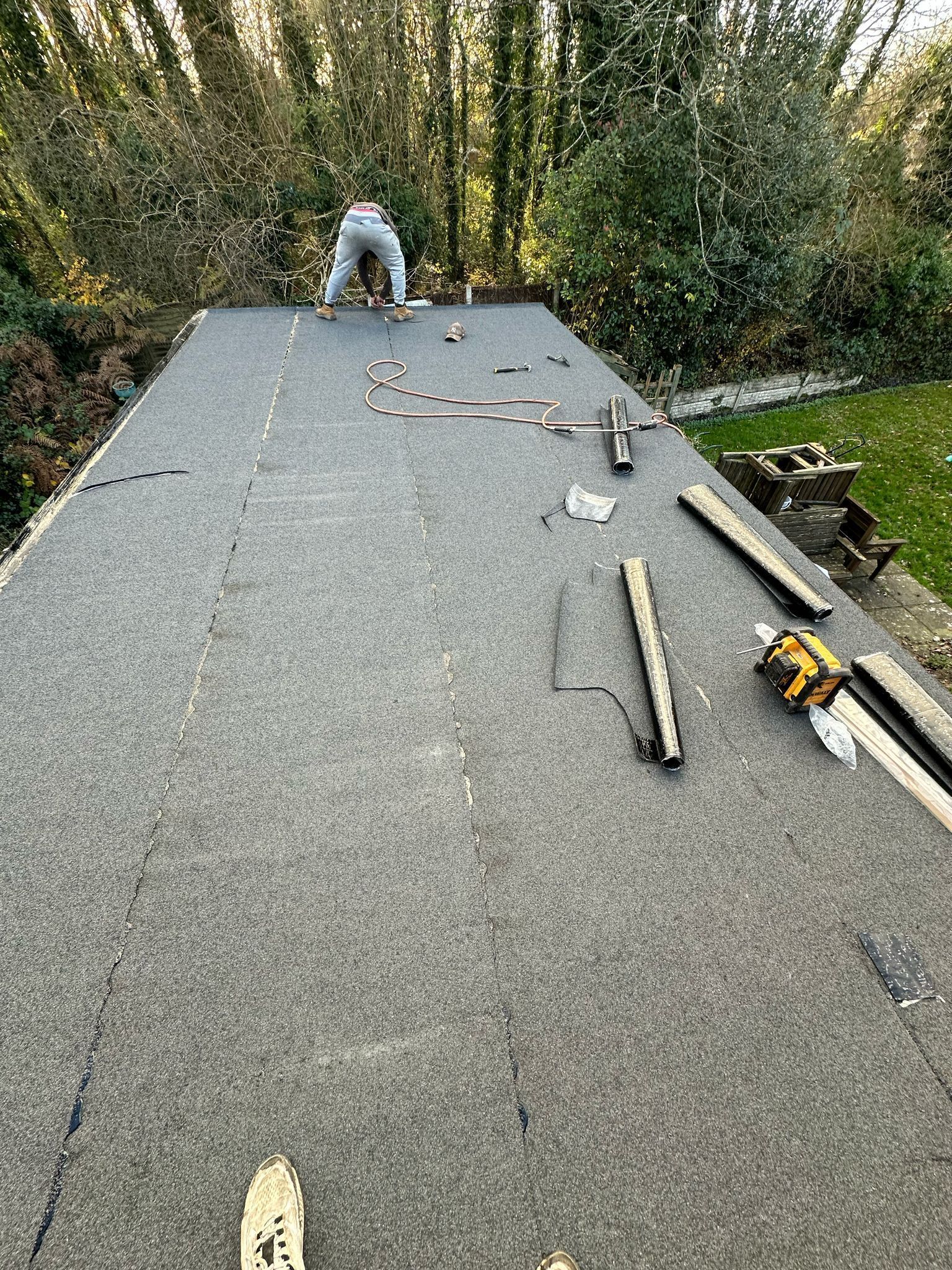 Roofer in Wimbledon installing new felt on a large flat roof.